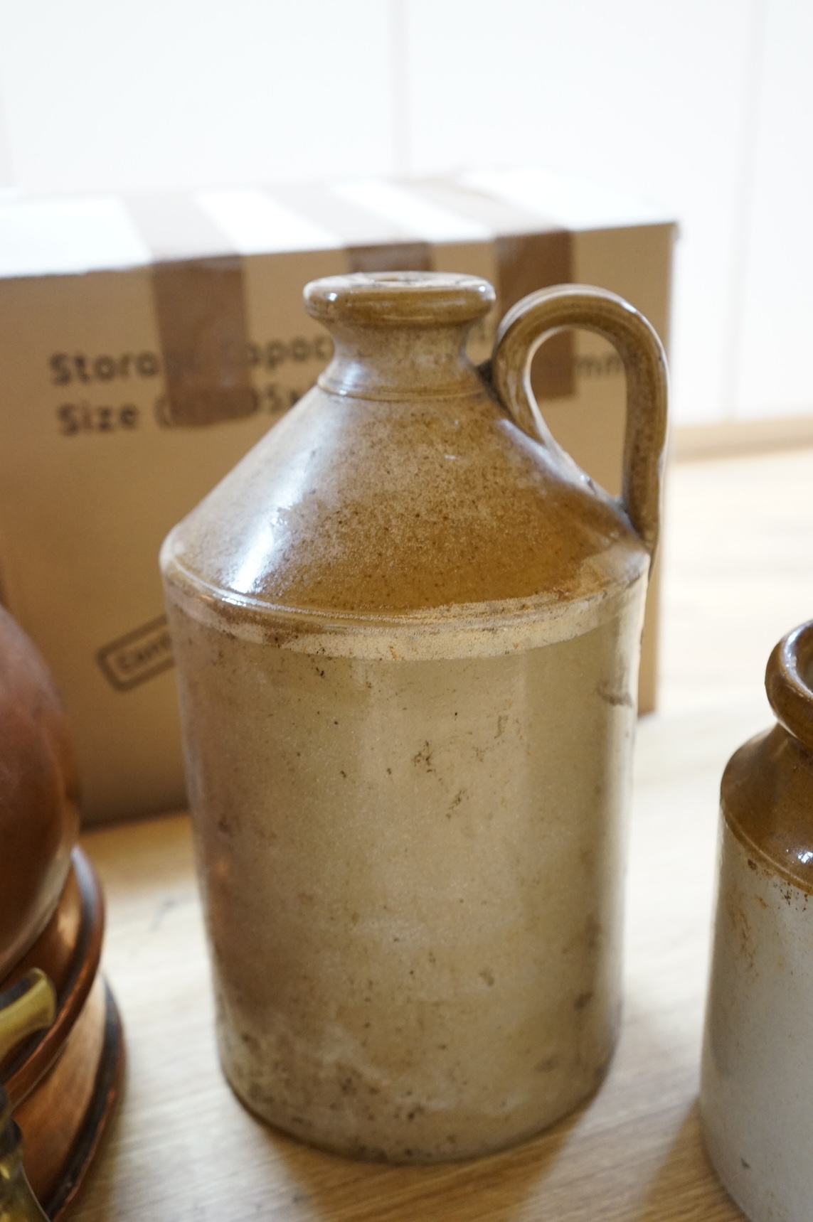 Three graduated copper haystack measures, H 39cm x W 40cm (inc spout), H 35cm x 25cm and H25cm x 18cm, Three stoneware jars H 32cm x W 20cm (two jars), H 20cm x W 16cm (1 jar)
